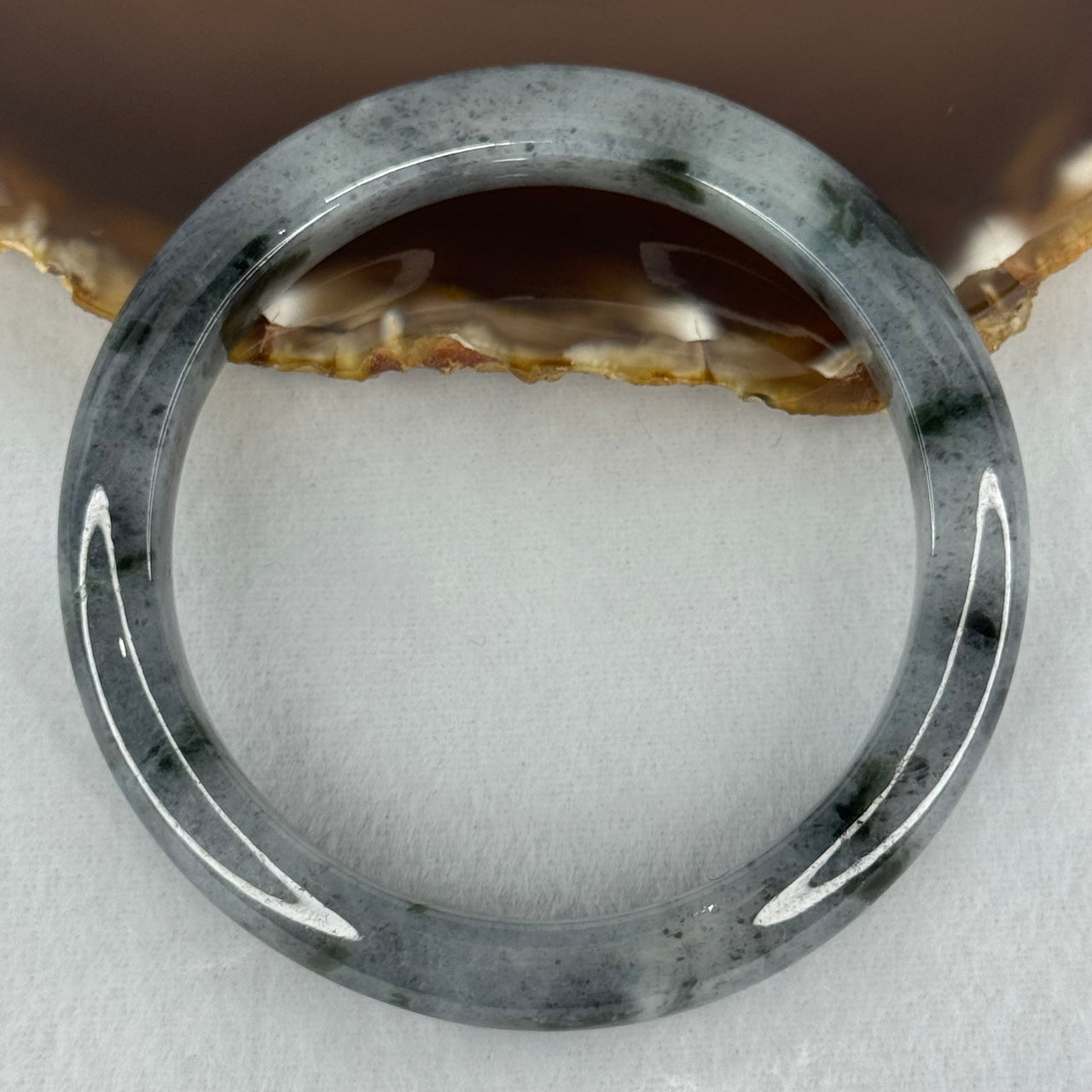 Type A Translucent Faint Grey with Greyish Black Patches Jadeite Bangle Internal Diameter 58.55mm 289.81cts 58.40g 11.8 by 8.6mm With NGI Cert 32885981 (Very Slight Internal Lines)