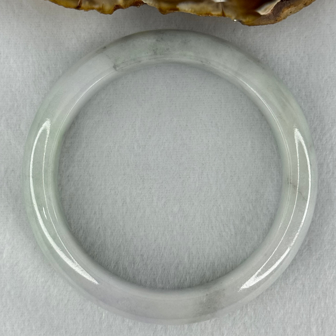 Type A Translucent Faint Blueish Green with Patches of Light Grey and Faint Lavender Jadeite Bangle Internal Diameter 56.95mm 344.09cts 69.22g 14.6 by 8.9mm With NGI Cert No 32886054 (Very Slight Internal Line)